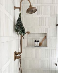 a bathroom with white tiled walls and flooring, including a shower head and hand held faucet