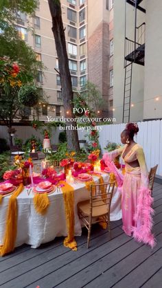 a woman standing next to a table covered in pink and yellow decorations