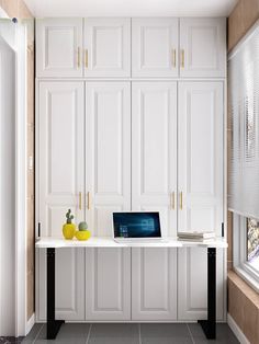 a laptop computer sitting on top of a white desk in a room with lots of cupboards