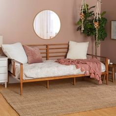 a day bed with pillows and blankets on it in front of a round mirror over a dresser