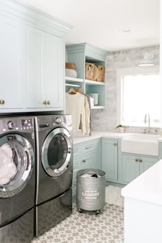 a washer and dryer in a laundry room next to a sink with blue cabinets