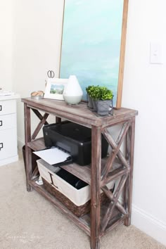 a wooden table with drawers and a painting on the wall behind it, next to a mirror