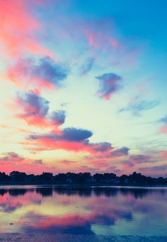 the sky is reflected in the water at sunset or sunrise time as seen from across the lake