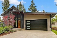 a house with a garage in front of it and landscaping around the entrance to the home