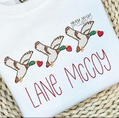 an embroidered t - shirt that says lane mccy with three doves on it