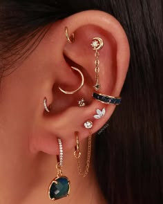 a woman wearing three different ear piercings and one has a heart shaped stone in the middle