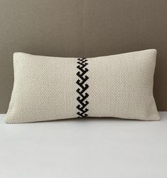 a white and black pillow sitting on top of a bed