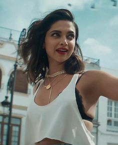 a woman wearing a white top and black pants posing for a photo in front of a building