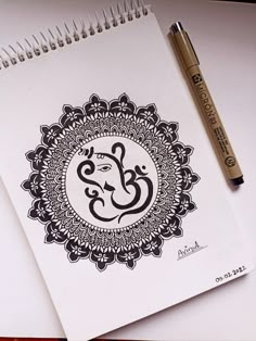 a spiral notebook with an omg symbol on it and a pen next to it