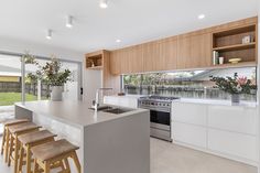 a kitchen with an island counter and stools in front of the window that looks out onto the back yard