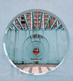 a circular metal object on the side of a building with blue and red bars around it