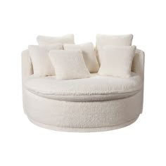 a white round couch with lots of pillows on it's back and side ends