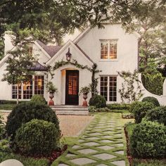 a white house with lots of windows and plants around it's front entrance area