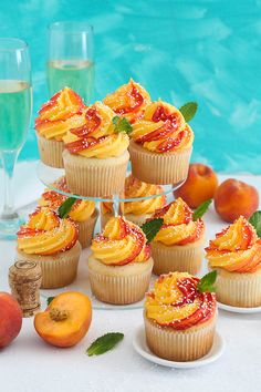 cupcakes and peaches on a table next to a pool with water in the background