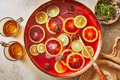 blood oranges, lemons and herbs are arranged on a platter with tea