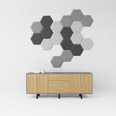 a modern sideboard with several hexagonal tiles on the wall above it and a cabinet below