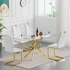 a glass dining table with gold legs and white chairs