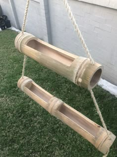 two wooden tubes hanging from a rope in the grass