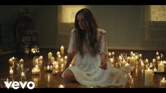 a woman sitting on the floor surrounded by candles