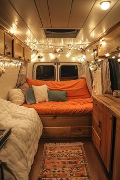 the inside of a camper with lights strung from it's ceiling and bed