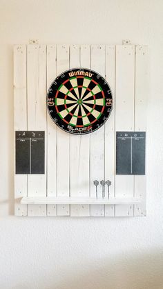 a dart board mounted to the side of a white wall with three darts on it