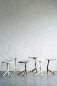 three small tables sitting next to each other in front of a white brick wall and floor