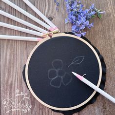 a black chalkboard with flowers and pencils on it next to some white sticks