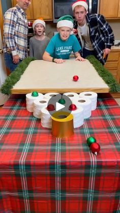 a group of people standing around a table with toilet paper and christmas decorations on it