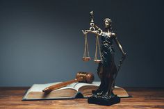 a statue of lady justice holding the scales of justice in front of an open book