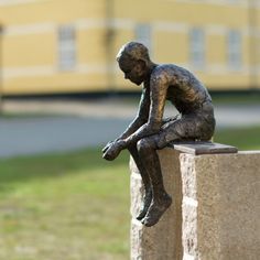 a bronze statue of a boy sitting on a block