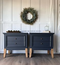 two blue nightstands side by side with a wreath on the wall