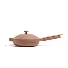 a small sauce pot with a wooden spoon in the middle and lid on it's side