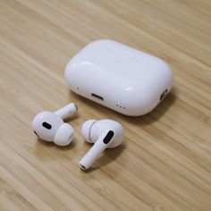 an apple airpods sitting on top of a wooden table next to another pair of ear buds