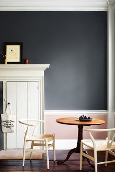 two chairs sitting at a table in front of a fireplace with a framed picture on the wall