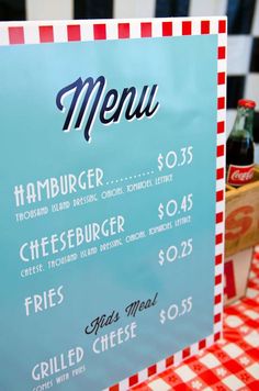 a restaurant menu sitting on top of a red and white checkered tablecloth covered table