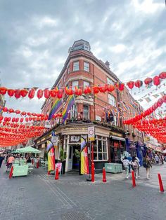 the street is decorated with red, yellow and orange paper lanterns hanging from it's sides