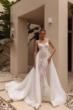 a woman standing in front of a building wearing a wedding dress