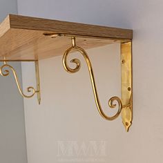 a wooden shelf with metal brackets hanging from it's sides on a white wall