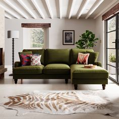 a living room with a large green couch and pillows on the floor next to a window