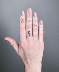 a woman's hand with tattoos on her fingers and the moon, sun and stars