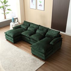 a large green couch sitting on top of a wooden floor next to a white rug