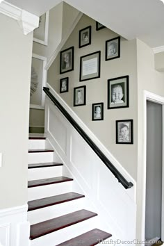 a staircase with pictures on the wall and framed photos on the wall above it, along with stairs leading up to an upstairs landing