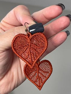 a woman's hand holding two heart shaped earrings