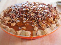 a pie with pecans and caramel drizzled over it on a plate