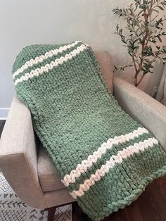 a green and white blanket sitting on top of a chair next to a potted plant