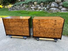 two wooden dressers sitting next to each other in front of a rock wall and grass