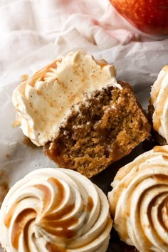 some cupcakes with frosting and an apple in the background