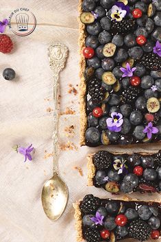 fruit tart with berries, blueberries and raspberries on it next to a spoon