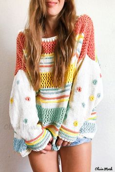 a young woman is posing with her hands on her hips and wearing a multicolored sweater