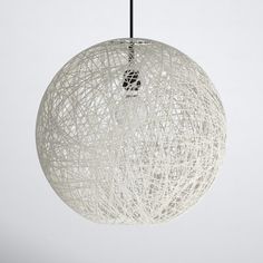 a white ball shaped light hanging from a black wire cord on a gray background with an empty space in the middle